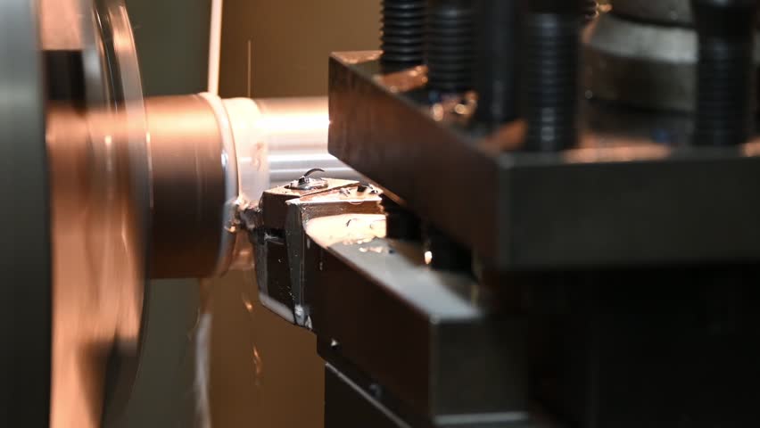 Pan scene the lathe machine finish cut metal shaft parts with liquid coolant method. The metalworking process by turning machine.