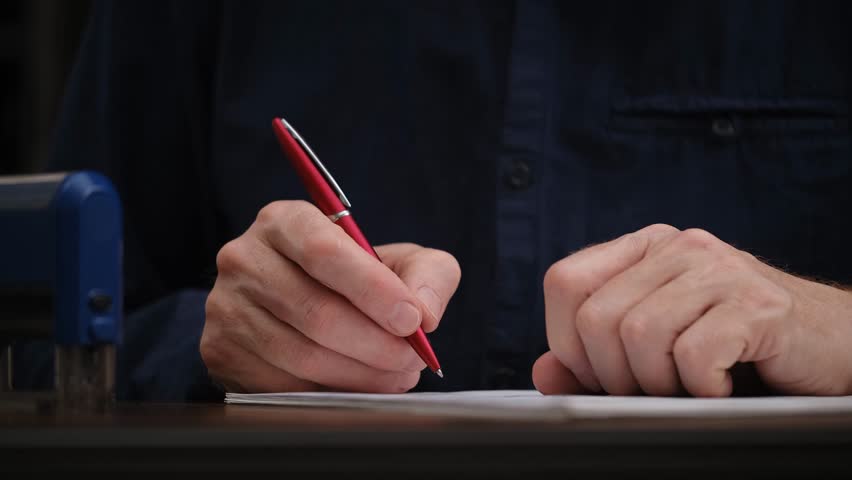 close-up of a man's hands signing an official document and putting a seal. unrecognizable businessman signs a contract on his desktop. concept of document management. front view.