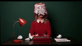 A white woman in a red dress works on a typewriter in an office with green walls. A wastepaper basket is on her head, symbolising burnout and workplace exhaustion - Powered by Shutterstock - Get 15% off with code: PIKWIZARD15