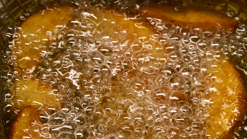 Close-up slow motion fried crispy potato wedges deep frying in oil. French fries