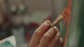 Hand of artist using brush to apply orange paint to canvas, painting fine details with smooth strokes. Extreme close-up view - Powered by Shutterstock - Get 15% off with code: PIKWIZARD15