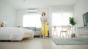 Caucasian housekeeper mopping the floor while dancing in lively mood at modern apartment. Happy energetic mother or cleaner enjoy cleaning the living room while moving to music. Lifestyle. Pedagogy. - Powered by Shutterstock - Get 15% off with code: PIKWIZARD15