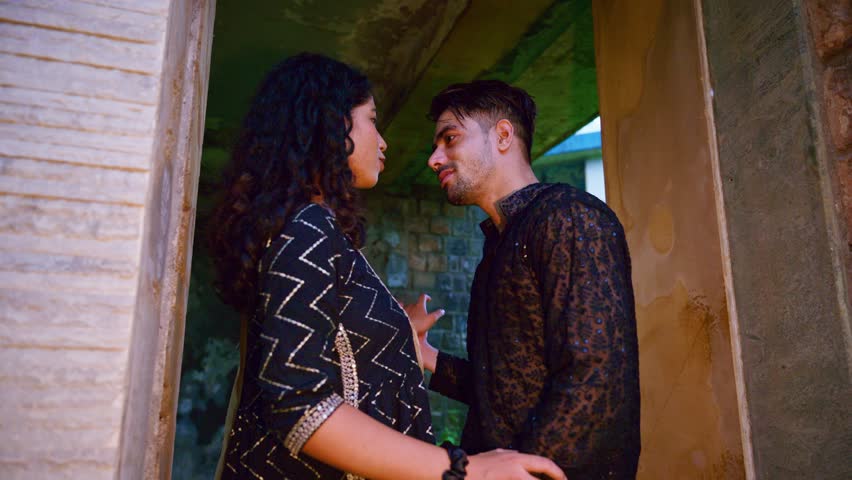 Lovers meet at abandoned spot for a private date, Couple stands dating intimately in forgotten place, Pair talk and smile as they see each other, Duo holding hand playfully, Caresses with deep emotion