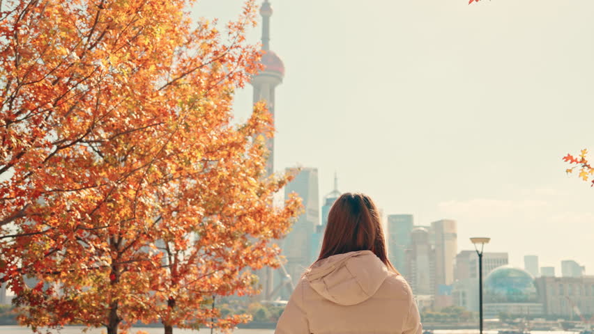 woman traveler visiting in Shanghai, China. Female Tourist with backpack sightseeing Shanghai view of Lujiazui in The north Bund of Shanghai in Autumn. landmark and popular for tourism attractions