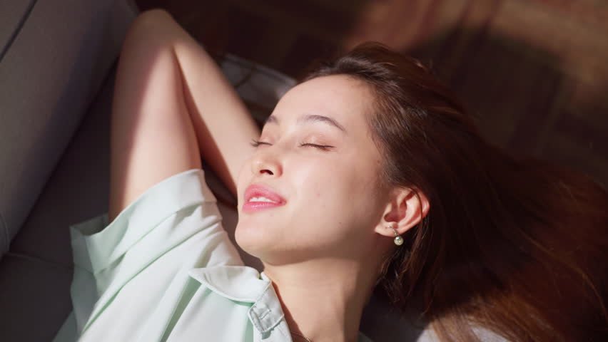 A woman enjoys a peaceful afternoon embodying relaxation and joy in a serene indoor setting.
