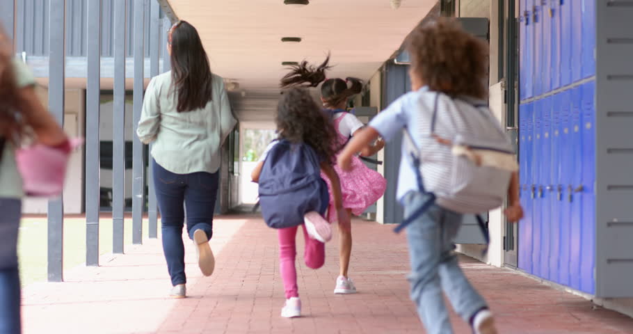 Running down school hallway, children with backpacks heading to class. Education, back to school, students, hurry, learning, excitement, unaltered, slow motion