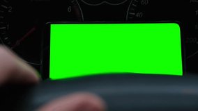 Man using phone with blank green background. Smartphone lies on car dashboard. Automotive technology. GPS navigation. Mobile apps for drivers. Using gadgets while driving. Smartphone chroma key - Powered by Shutterstock - Get 15% off with code: PIKWIZARD15