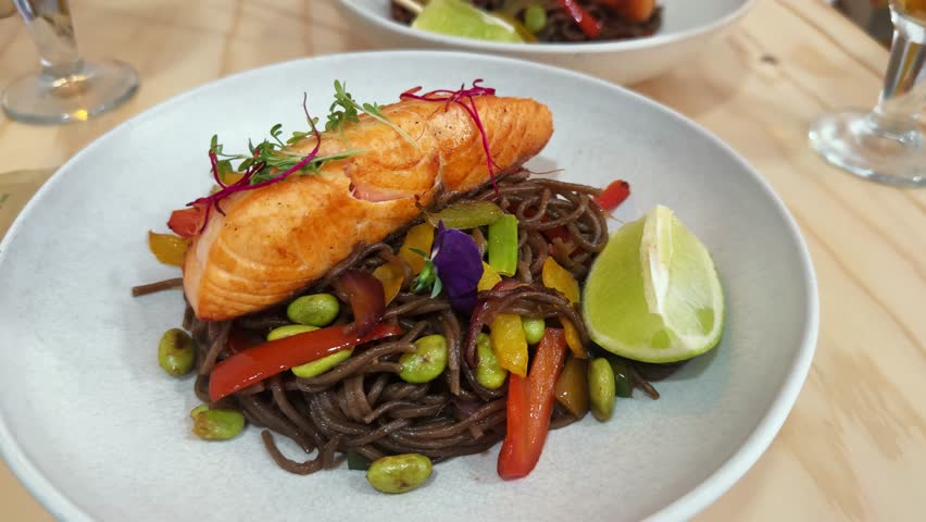 Black cuttlefish ink pasta with salmon fish, lemon to the plate in cafe healthy food cafe. High quality 4k footage