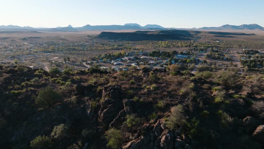 Flying over mountain to reveal small rural West Texas Town, Fort Davis near Big Bend National Park, drone push in at golden hour in 4k