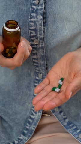 Female hands open jar and pour out pills into palm. Pills and drugs medicament vitamins. Take medicine take pill. Medicine and health care. Vertical shot