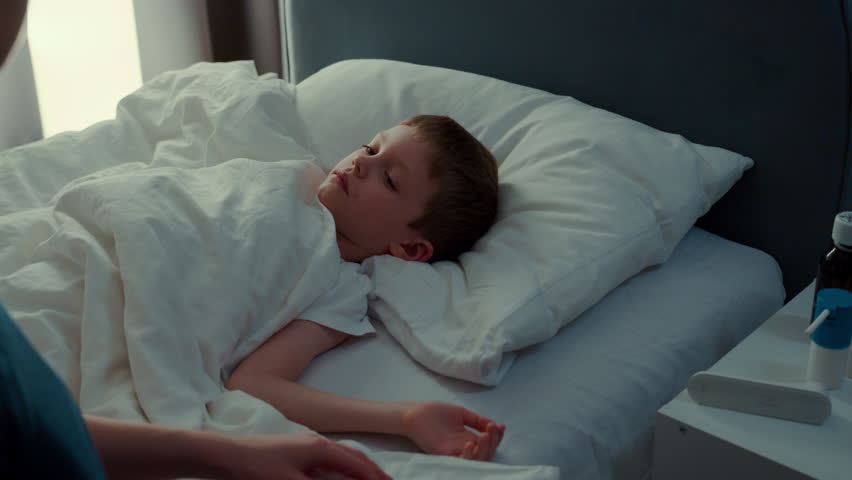 Sick child, thermometer reading high, mother's concern for her daughter's health, and check-up for virus in home. child is resting with flu while mother takes temperature in bedroom of their home.