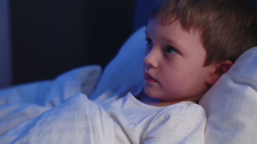 Mother pouring cough syrup into a spoon and giving it to her sick child. Sick child concept. Mother gives her 7-year-old baby boy medicine in the form of cough syrup on a spoon.
