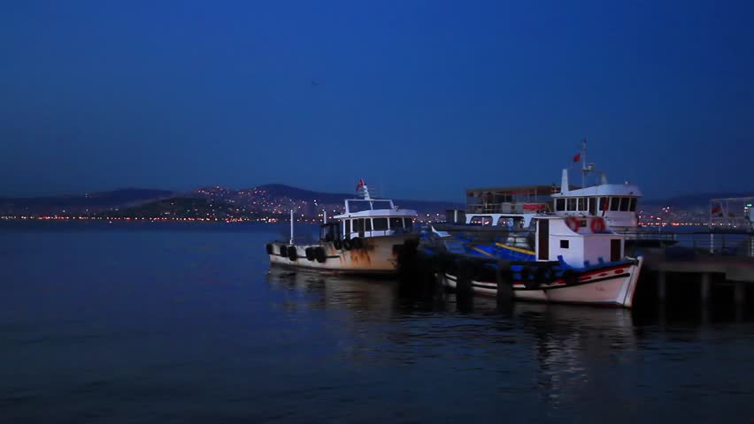 Fisher boats at berth in shore of Buyukada Island. Night scene with city lights