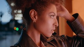 Gorgeous model posing at night gazing at showcase with warm yellow light closeup. Portrait african american woman wearing leather jacket looking camera. Chic curly lady standing at dark city street. - Powered by Shutterstock - Get 15% off with code: PIKWIZARD15