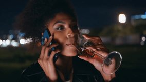 Closeup girl talking cellphone drinking champagne at night town party. Portrait relaxed african american woman calling smartphone at party. Curly beautiful lady have phone conversation late evening. - Powered by Shutterstock - Get 15% off with code: PIKWIZARD15