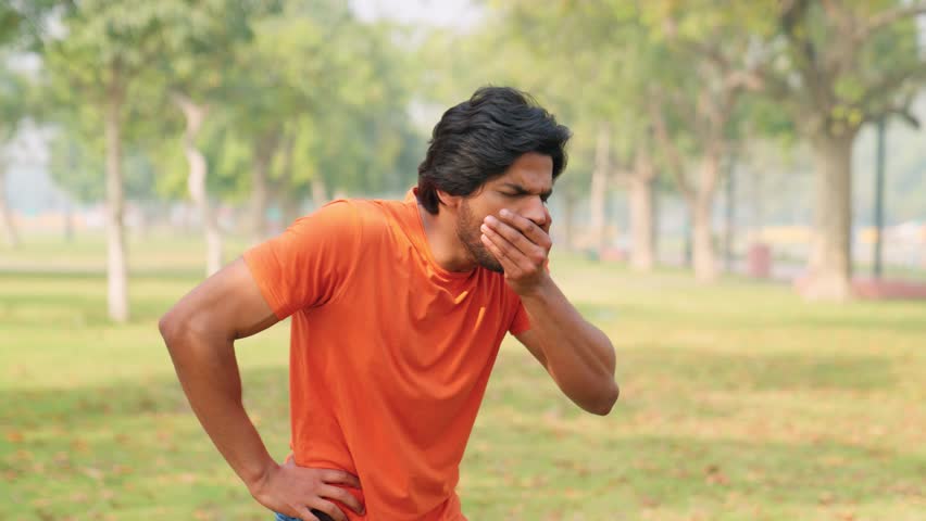 Young Indian Man in Orange T-Sjirt Coughing