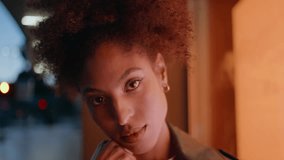 Woman face illuminated urban lights closeup. Portrait confident curly-haired model posing at evening street under showcase warm illumination. Gorgeous african american lady at dynamic city background. - Powered by Shutterstock - Get 15% off with code: PIKWIZARD15