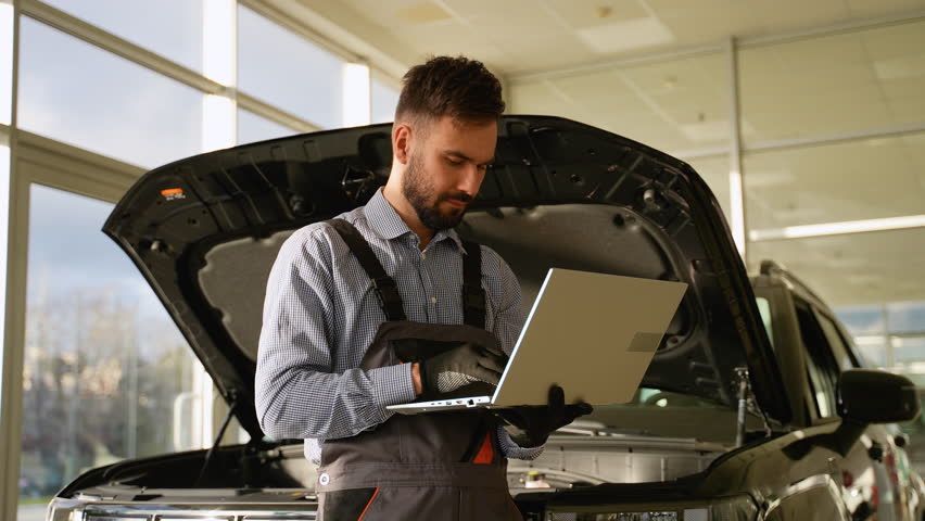 Mechanic diagnosing car engine issues using a laptop