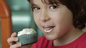 Child Eating Muffins Cupcakes Decorated With Sugar Cream. Boy Enjoying Vanilla Cupcakes with Frosting and Sprinkles. Unhealthy Junk Food. Hungry Sweet Tooth Child Bites Muffin with Sugar Frosting. - Powered by Shutterstock - Get 15% off with code: PIKWIZARD15