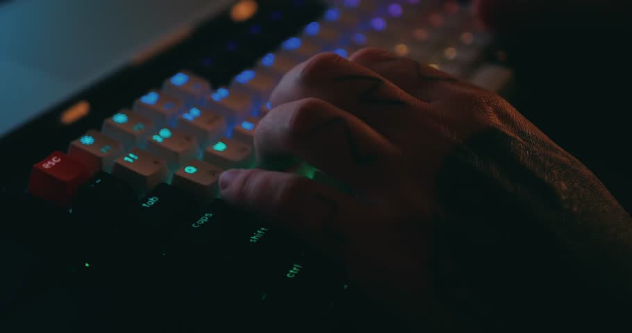 Hands typing on keyboard. Close up of professional mechanical keyboard with colorful LED backlight in multiple colors. Technology in gaming or developer industry. 