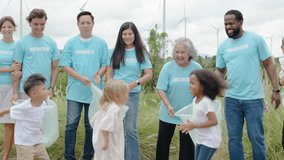 Group of volunteers families come together to collect trash and restore the natural landscape. Everyone actively participates, showcasing teamwork, environmentally,  pollution concept, wind turbine - Powered by Shutterstock - Get 15% off with code: PIKWIZARD15