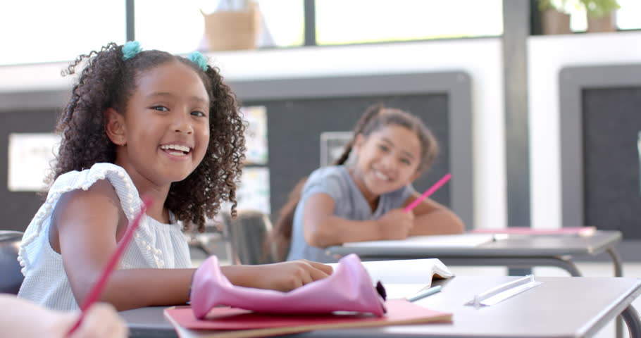 Biracial and Caucasian girls enjoy a school classroom activity. They