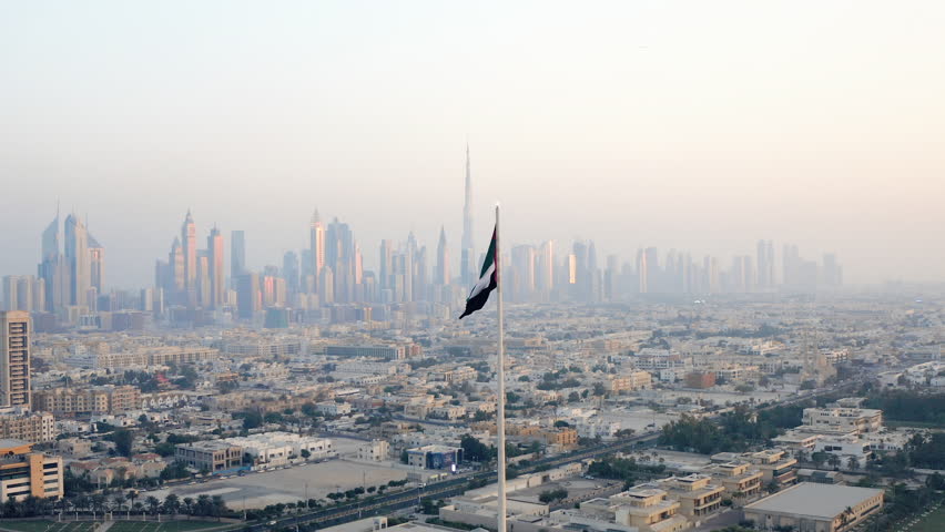 Aerial view of the United Arab Emirates' UAE national flag waving  with the Dubai skyline in background