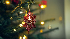  Close-up of a hand holding a red snowflake-shaped ornament while decorating a Christmas tree with warm lights. - Powered by Shutterstock - Get 15% off with code: PIKWIZARD15