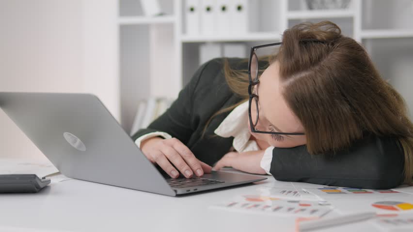 An exhausted office worker struggles with a mountain of tasks, highlighting the immense pressures of modern workplaces and the ongoing challenges of maintaining effective productivity