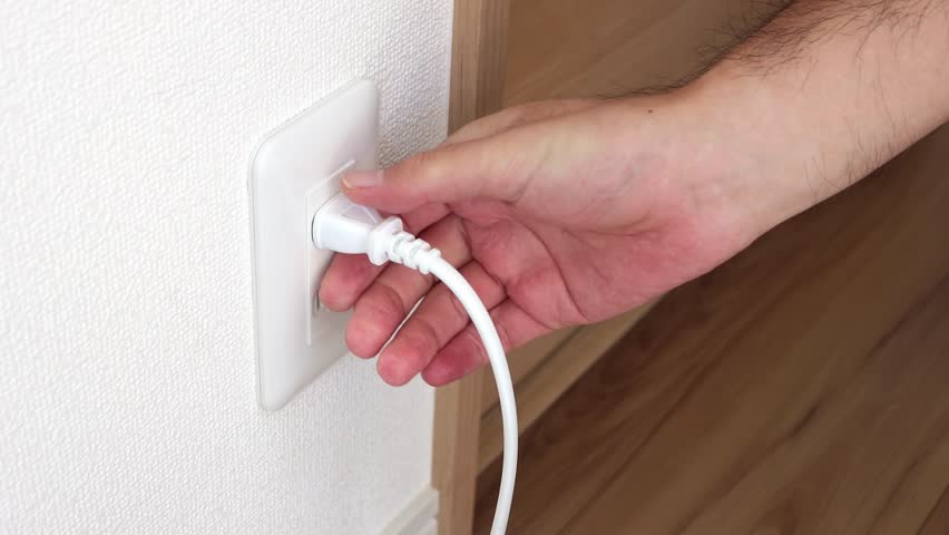 A man's hand plugging in and out an electrical outlet (Japanese, no face)