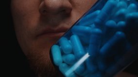 A Man Examining a Blue Bottle Filled with Capsules Showing the Smooth Texture and Deep Color of the Pills Nutritional Awareness - Powered by Shutterstock - Get 15% off with code: PIKWIZARD15