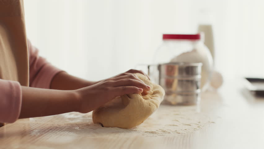 In a warm and inviting kitchen, a mother and daughter enjoy quality time baking together. They knead dough on a wooden counter, surrounded by baking ingredients and tools, creating sweet memories.