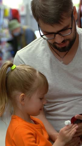 Father and child in shopping cart choose food in grocery department in supermarket. Concept of shopping products in store. Vertical shot
