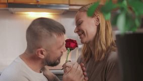 Loving wife giving red rose to husband in kitchen, expressing heartfelt valentine's day affection with gentle romantic gesture.Celebrating valentine's day or anniversary - Powered by Shutterstock - Get 15% off with code: PIKWIZARD15