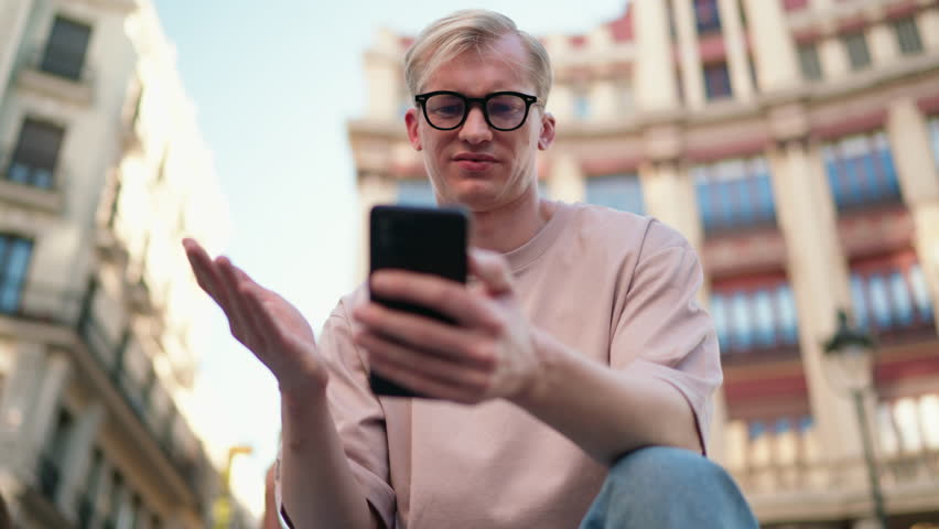 Young male blogger looking confused and annoyed while reading unexpected or negative comments on his social media profile. Caucasian man feeling frustrated and sad while using his smartphone device