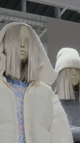 No people vertical shot of white mannequin with blond wig presenting white warm soft jacket in modern clothes shop, new winter collection, copy space