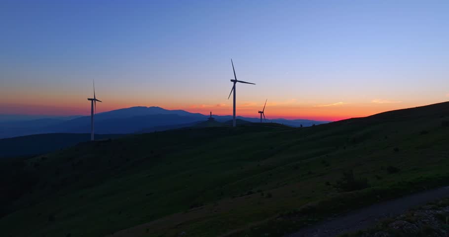 Sun Setting Behind Mountains Aerial Parallax On High Altitude Wind Turbine Farm Bulgaria Drone