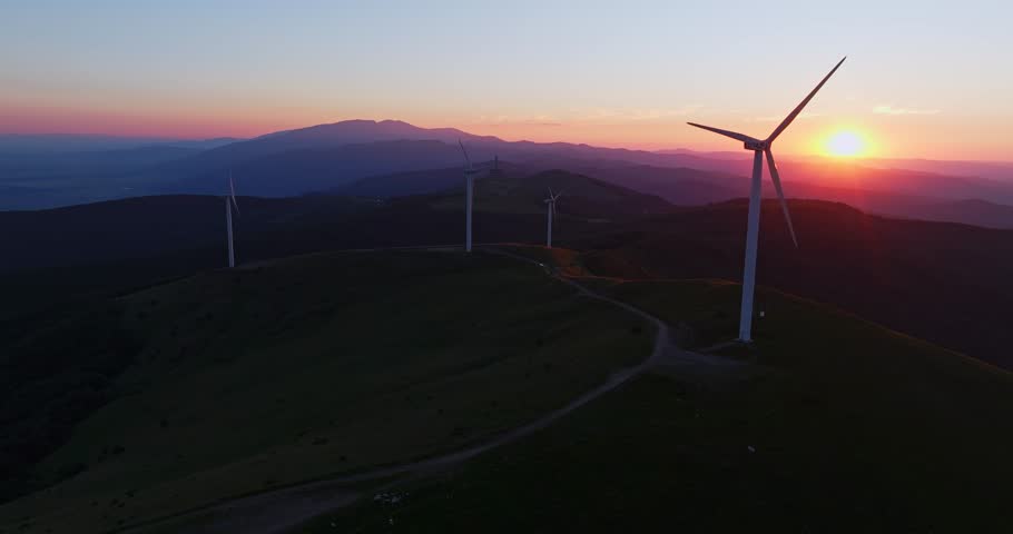 Vast Mountain Peak Landscape Wind Turbine Generators Spinning Vibrant Sunrise Aerial Drone