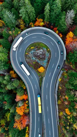 Aerial drone view winding mountain road between autumn trees. Vehicles driving through the curve. Serpentine road Black Forest southern Germany. High quality 4k footage