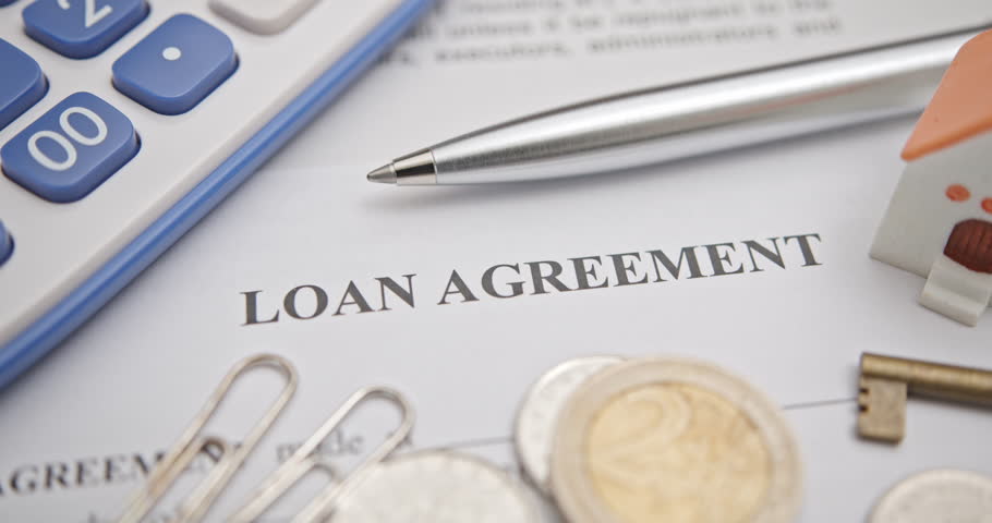 Loans, financial agreements, and real estate transactions. A close-up of a loan agreement document with a calculator, coins, a house model, and a key, representing financial planning, real estate, etc
