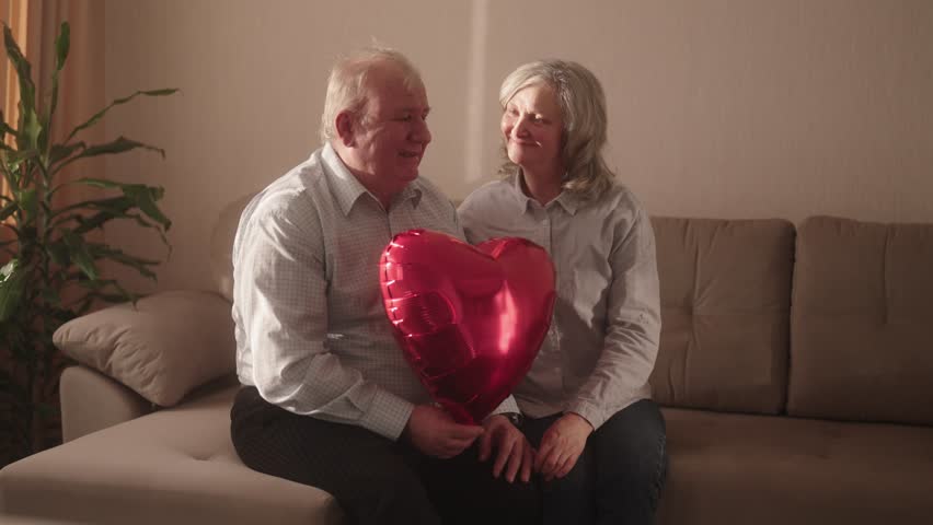 Happy senior couple holding a heart balloon, celebrating Valentine