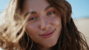 Wavy hair model smiling camera at sea shore portrait. Seductive romantic girl posing sandy beach closeup. Cheerful woman relaxing sunlight feeling ocean breeze. Pretty lady enjoying summer vacation - Powered by Shutterstock - Get 15% off with code: PIKWIZARD15