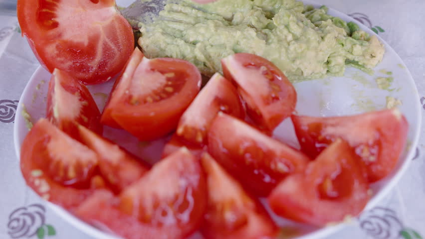A Plate of Sliced Tomato Wedges Arranged Around Mashed Avocado, Ready for Serving, Bright Red and Green Colors, Close-Up