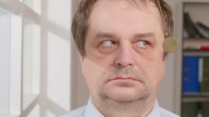 Man in hypnosis session with his eyes follows swinging hypnotic pendant on chain in front of face.