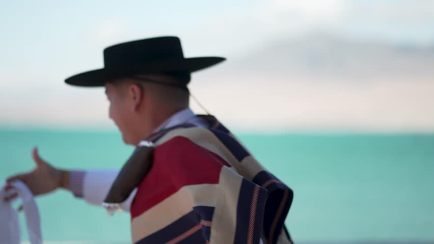 Young dancer wearing traditional chilean clothing performs the national dance, cueca, by the ocean