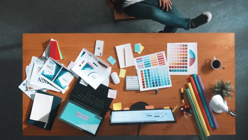 Top view of smart caucasian business man put leg on meeting table with color palettes, paper and equipment for design logo graphic. Aerial view of relaxed of business man sleeping at chair Symposium.