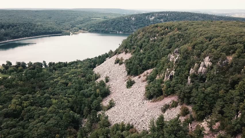 Aerial view of a rocky bluff surrounded by lush forest near Devils Lake in Wisconsin, highlighting natural beauty and tranquility.