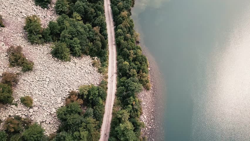 Drone footage of Devils Lake, Wisconsin, capturing a road winding along the forested shoreline and calm waters.