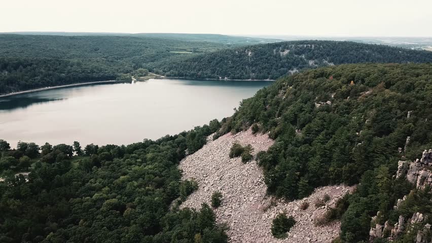 A breathtaking aerial view of Devils Lake, Wisconsin, showcasing rocky cliffs, lush forests, and calm reflective waters.
