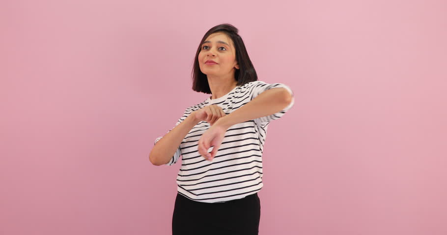 Happy smiling young short hair cute Asian woman dancing alone enjoying weekend, having fun express feel pleasure looking at camera, isolated over pink background.